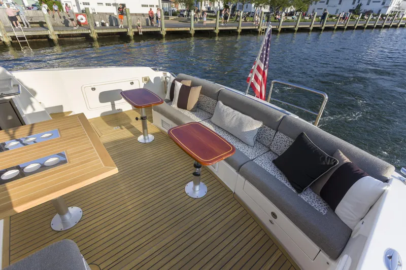 Slide: The Image of Luxurious 2016 Riviera 5000 Sport Yacht deck with seating, tables, and American flag. - 12