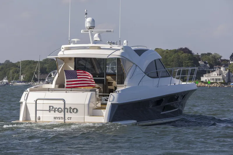 Slide: The Image of 2016 Riviera 5000 Sport Yacht cruising with American flag, scenic coastal background. - 2