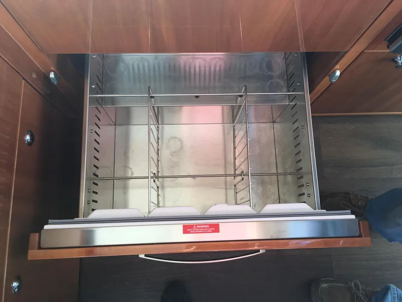 Slide: The Image of Open drawer in 2016 Riviera 5000 Sport Yacht, featuring stainless steel interior and wooden finish. - 25