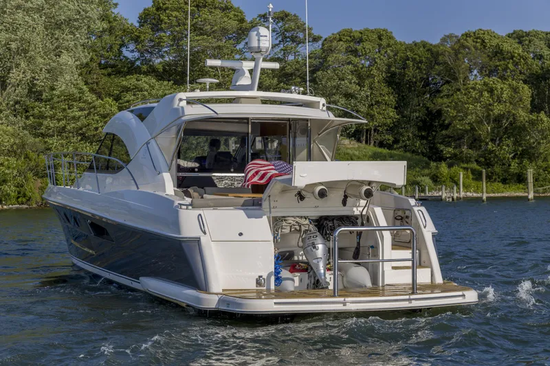 Slide: The Image of 2016 Riviera 5000 Sport Yacht cruising on a scenic waterway with lush greenery. - 5