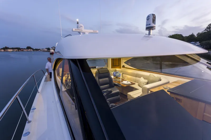 Slide: The Image of 2016 Riviera 5000 Sport Yacht on calm water at dusk, featuring luxurious interior seating. - 7