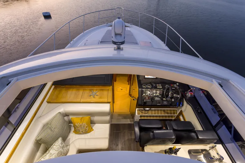 Slide: The Image of 2016 Riviera 5000 Sport Yacht interior with helm, seating, and elegant design at sunset. - 8
