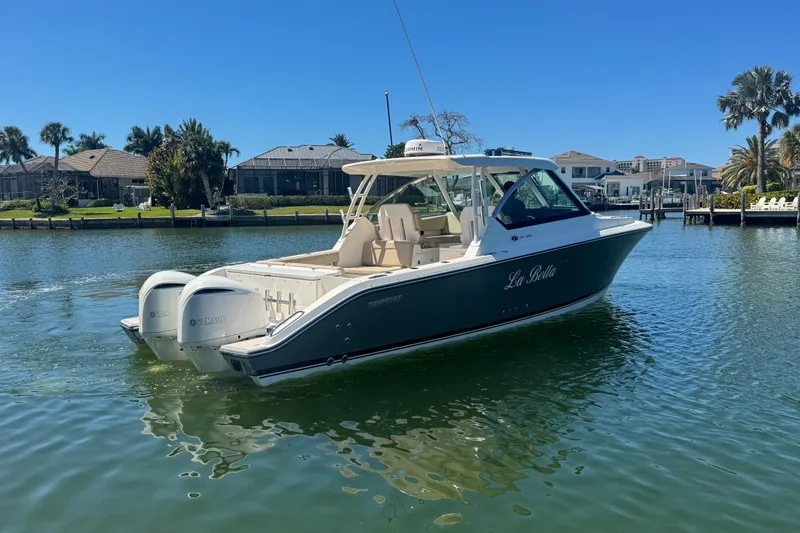 Slide: The Image of 2016 Pursuit DC 325 Dual Console boat on calm water, sunny day, waterfront homes in background. - 11