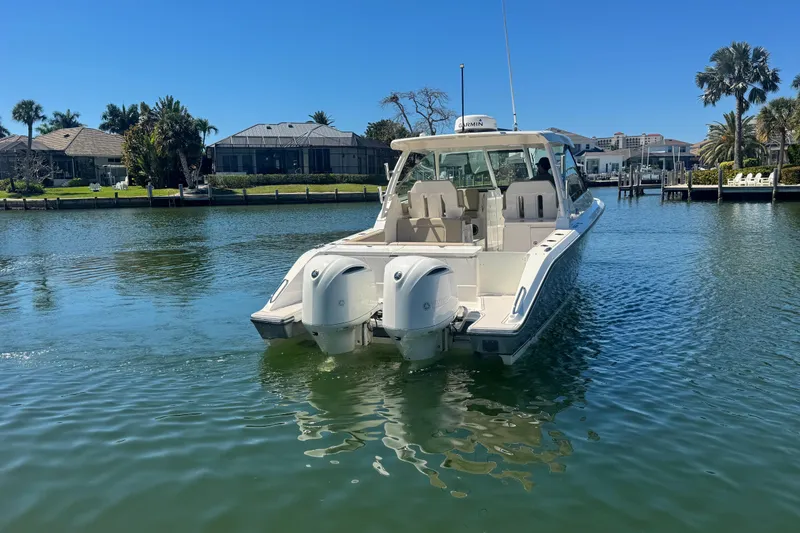 Slide: The Image of 2016 Pursuit DC 325 Dual Console boat on calm water, surrounded by waterfront homes. - 12