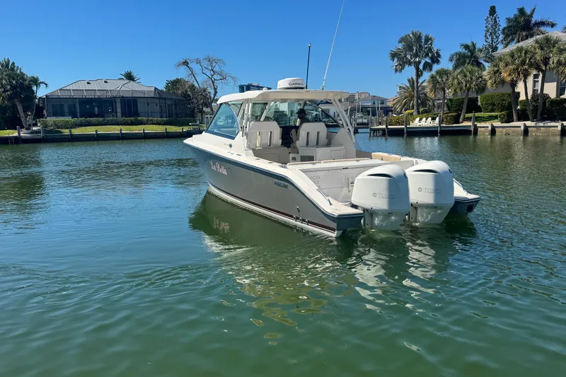 Slide: The Image of 2016 Pursuit DC 325 Dual Console boat on calm water, surrounded by waterfront homes. - 14
