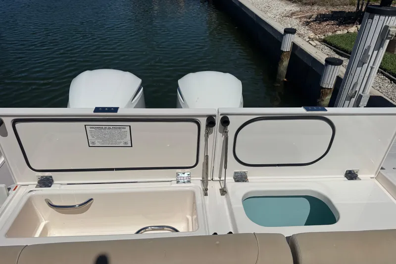 Slide: The Image of 2016 Pursuit DC 325 Dual Console boat with open storage compartments by the water. - 20