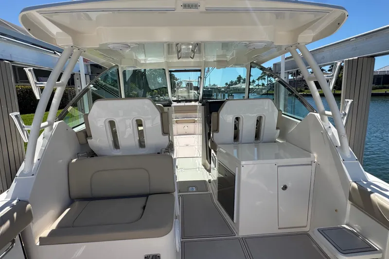 Slide: The Image of 2016 Pursuit DC 325 Dual Console boat interior with seating and storage, docked by the water. - 21