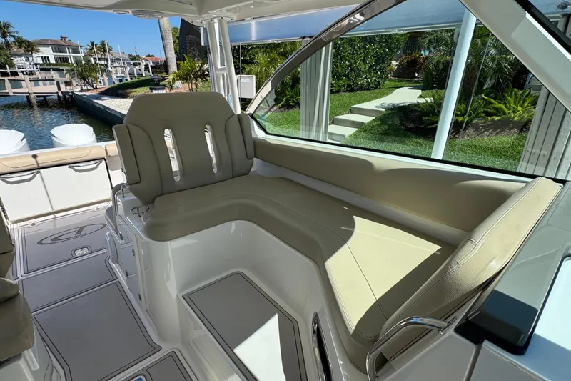 Slide: The Image of 2016 Pursuit DC 325 Dual Console boat interior with beige seating and waterfront view. - 23
