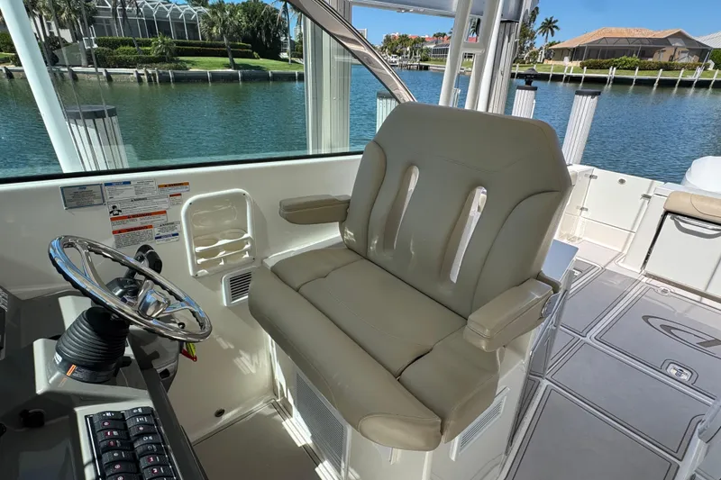 Slide: The Image of Helm seat of 2016 Pursuit DC 325 Dual Console boat with waterfront view. - 24