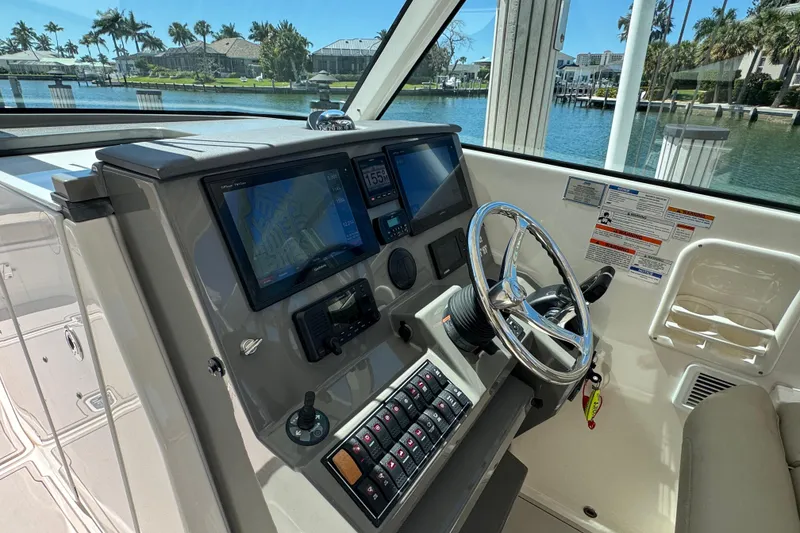 Slide: The Image of 2016 Pursuit DC 325 Dual Console boat cockpit with steering wheel and navigation screens. - 25