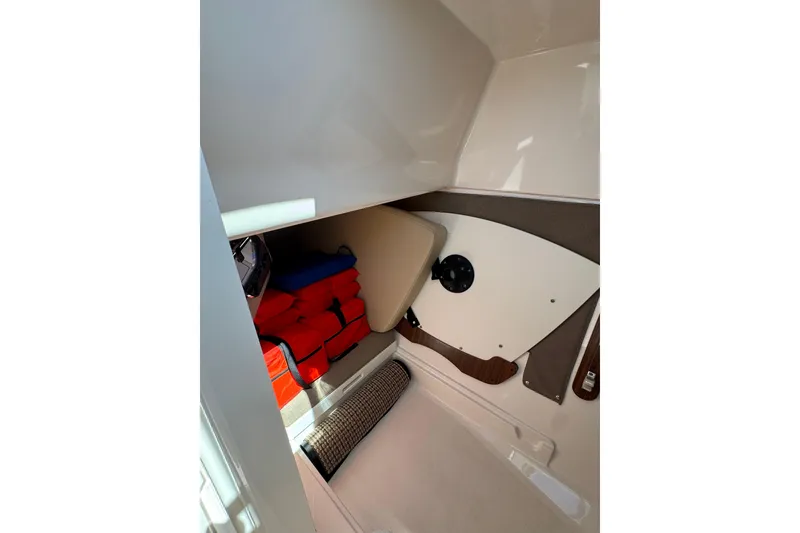 Slide: The Image of 2016 Pursuit DC 325 Dual Console interior storage with life jackets and cushions. - 29