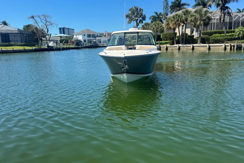 Slide: The Image of 2016 Pursuit DC 325 Dual Console boat on calm water near waterfront homes. - 3