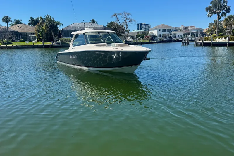 Slide: The Image of 2016 Pursuit DC 325 Dual Console boat on calm water near waterfront homes. - 35