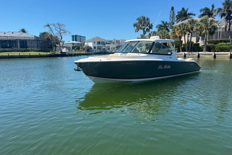 Slide: The Image of 2016 Pursuit DC 325 Dual Console boat on calm water near waterfront homes. - 36