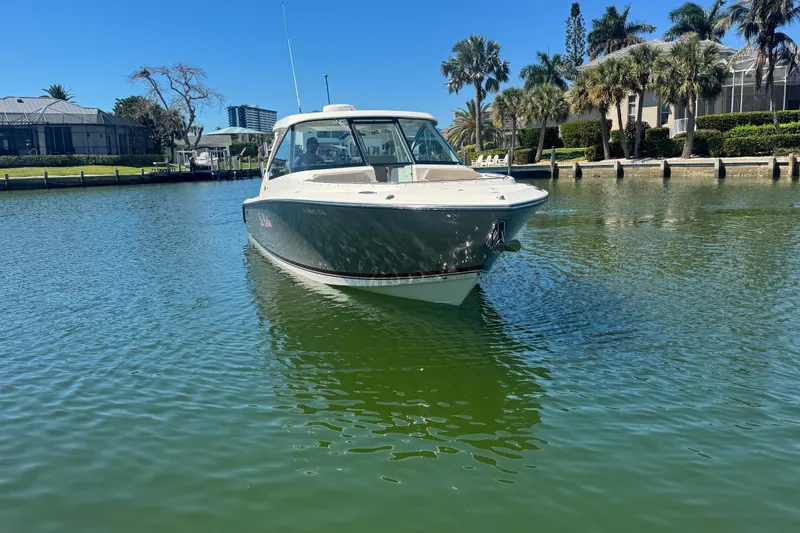 Slide: The Image of 2016 Pursuit DC 325 Dual Console boat on calm water, surrounded by palm trees. - 38
