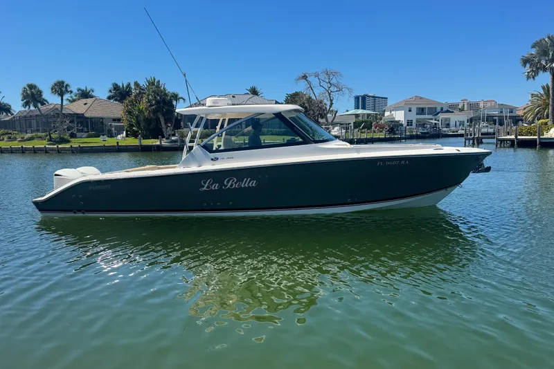 Slide: The Image of 2016 Pursuit DC 325 Dual Console boat on calm water, sunny day, waterfront homes in background. - 40