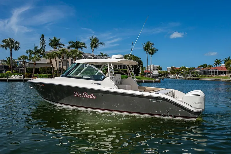 Slide: The Image of 2016 Pursuit DC 325 Dual Console boat on water, palm trees in background. - 46
