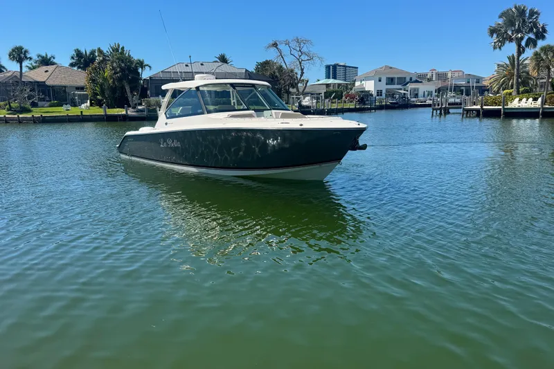 Slide: The Image of 2016 Pursuit DC 325 Dual Console boat on calm water near waterfront homes. - 7
