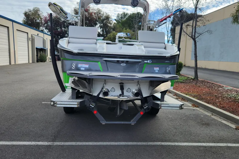 Slide: The Image of 2017 MasterCraft X23 boat on trailer, parked outdoors near industrial buildings. - 2