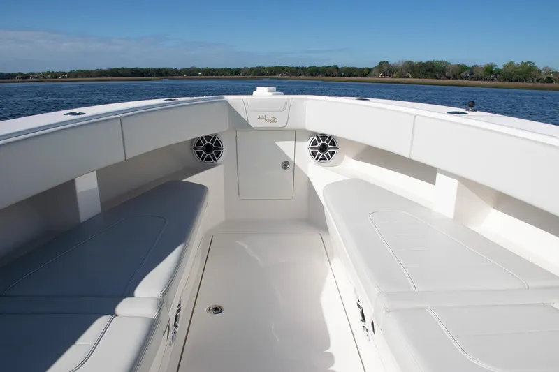 Slide: The Image of 2022 SeaVee 322Z boat interior with white seating and speakers, on calm water. - 20