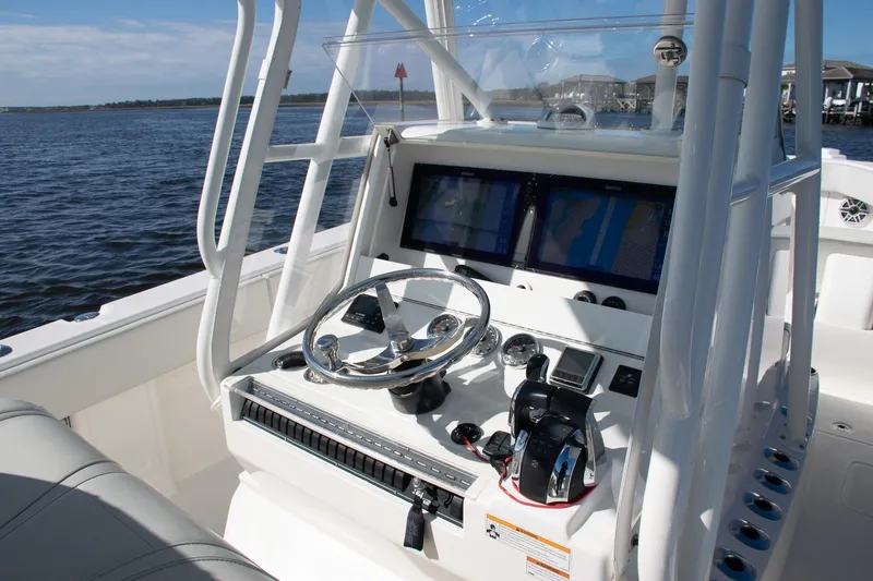 Slide: The Image of 2022 SeaVee 322Z boat helm with dual screens and steering wheel on open water. - 33