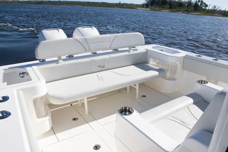 Slide: The Image of 2022 SeaVee 322Z boat interior with white seating and cup holders on a calm lake. - 36