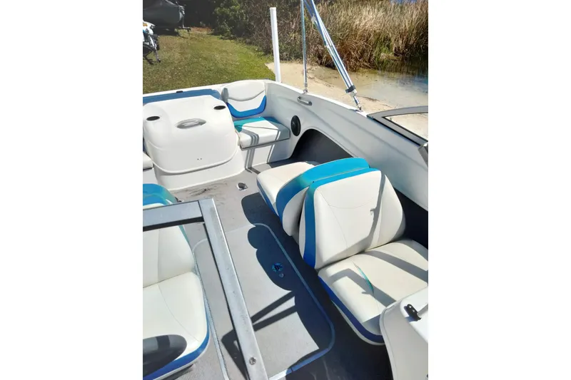 Slide: The Image of 2007 Bayliner 175 Bowrider interior with white and blue seating, near shoreline. - 19