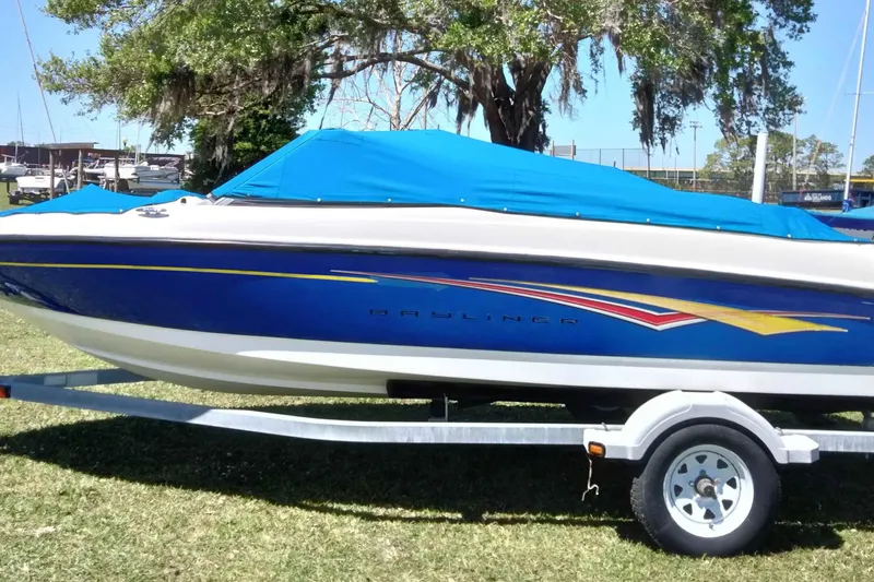 Slide: The Image of 2007 Bayliner 175 Bowrider boat with blue cover on trailer, parked on grass. - 23