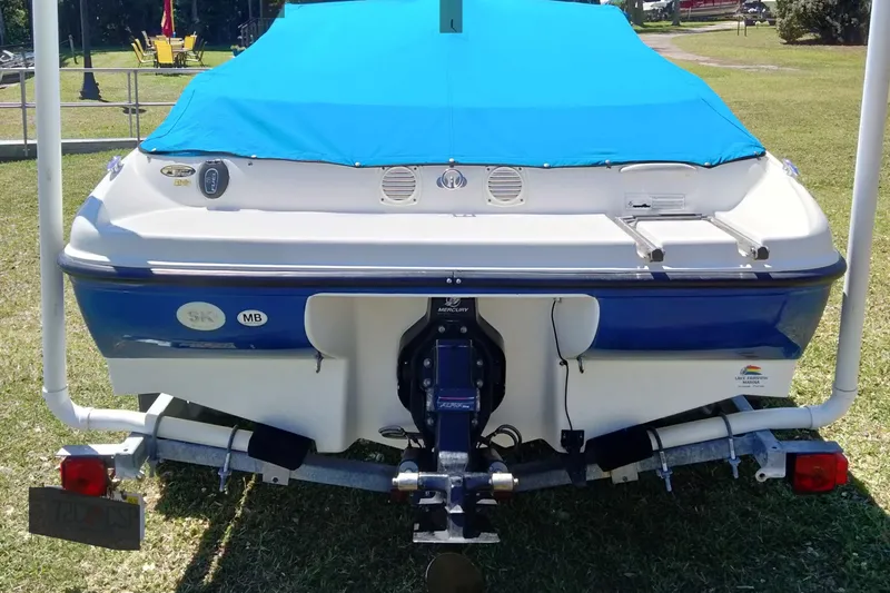 Slide: The Image of 2007 Bayliner 175 Bowrider with blue cover on trailer, parked on grass. - 24