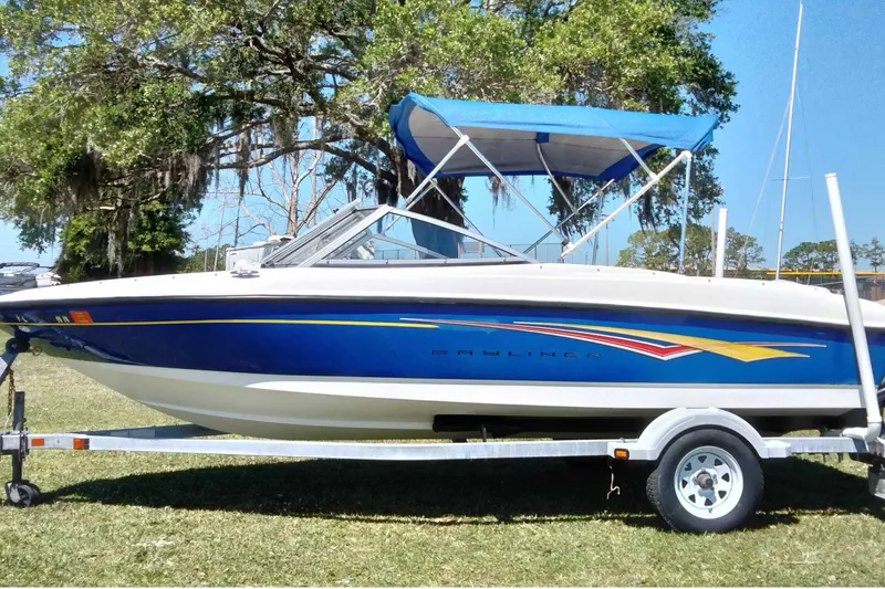 Slide: The Image of 2007 Bayliner 175 Bowrider boat on trailer with blue canopy, parked on grass. - 25