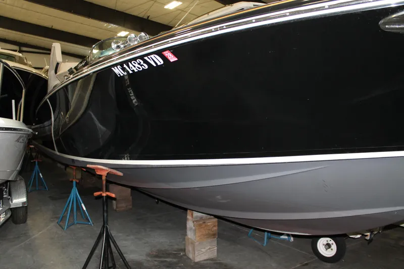 Slide: The Image of 2018 Chris-Craft Launch 34 boat in storage, black hull, supported by stands. - 13