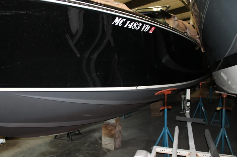 Slide: The Image of 2018 Chris-Craft Launch 34 boat in storage, black hull, supported by stands. - 14