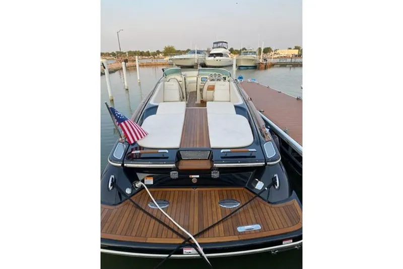 Slide: The Image of 2018 Chris-Craft Launch 34 boat docked, featuring elegant wood deck and American flag. - 8