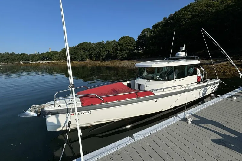 The Image of 2019 Axopar 28 Cabin boat docked by a serene lakeside with lush greenery. - 0