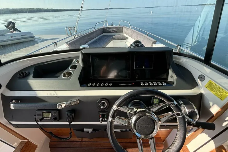 Slide: The Image of 2019 Axopar 28 Cabin boat dashboard with steering wheel and navigation controls. - 10