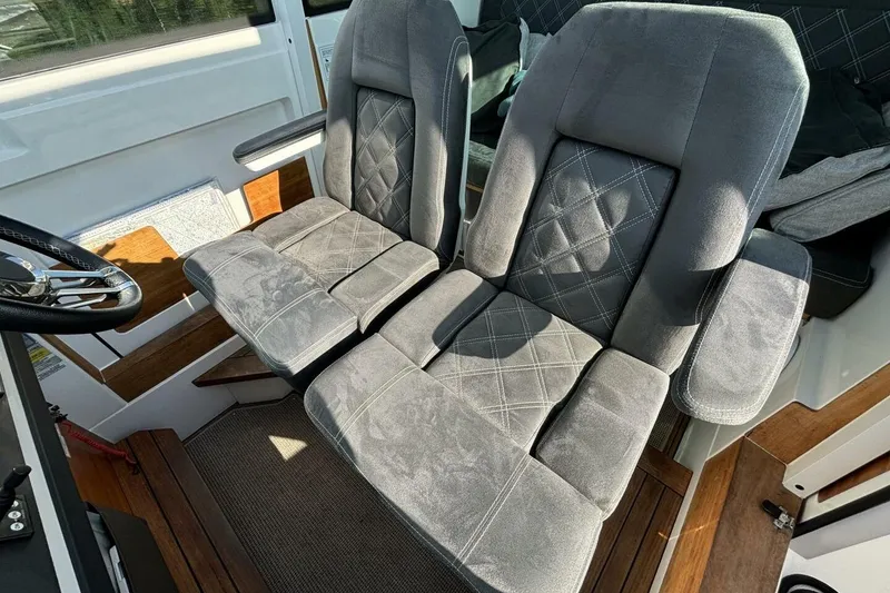 Slide: The Image of 2019 Axopar 28 Cabin interior with plush, gray seating and wooden accents. - 12