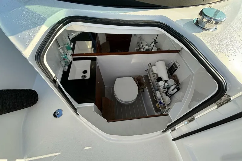 Slide: The Image of 2019 Axopar 28 Cabin boat bathroom with sink, toilet, and storage shelves. - 15