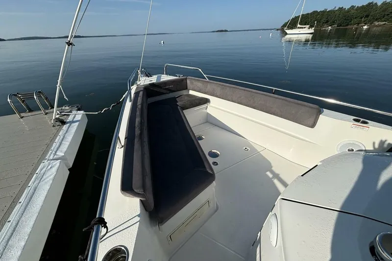 Slide: The Image of 2019 Axopar 28 Cabin boat docked on calm water with seating area. - 16