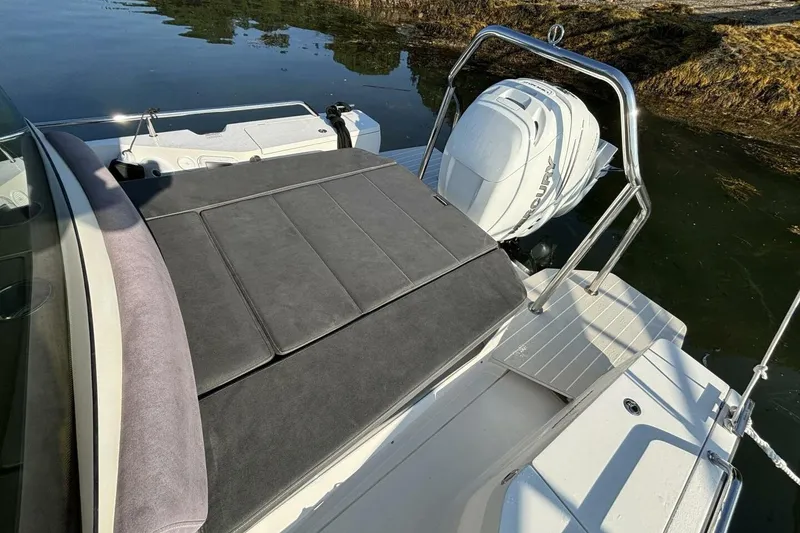 Slide: The Image of 2019 Axopar 28 Cabin boat with cushioned seating and outboard motor. - 18
