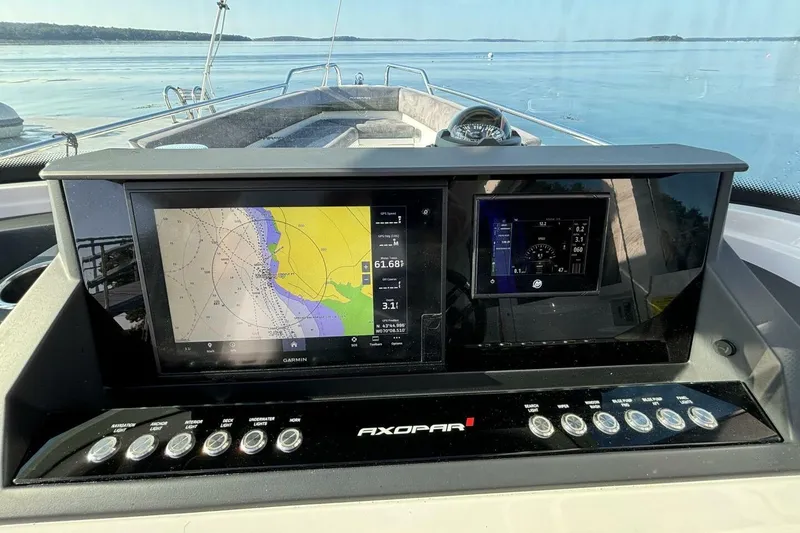Slide: The Image of 2019 Axopar 28 Cabin dashboard with navigation screens and controls on a calm water backdrop. - 22