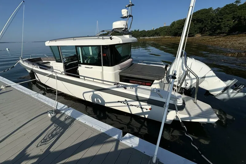Slide: The Image of 2019 Axopar 28 Cabin boat docked by a serene shoreline. - 5