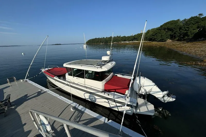 Slide: The Image of 2019 Axopar 28 Cabin boat docked by a serene lakeside with lush greenery. - 6