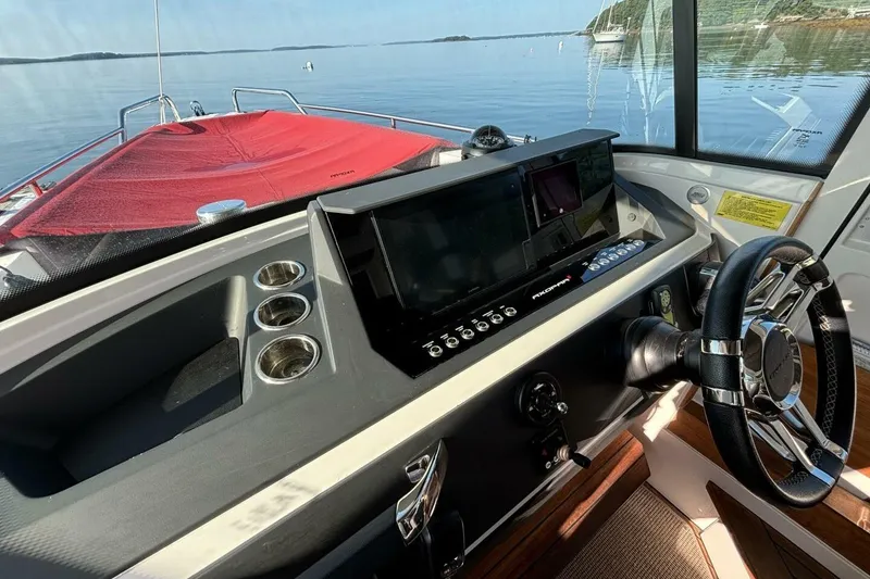 Slide: The Image of 2019 Axopar 28 Cabin boat dashboard with steering wheel and navigation controls. - 9