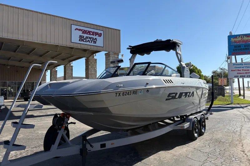 Slide: The Image of 2021 Supra SE 550 boat on trailer outside dealership under clear blue sky. - 4