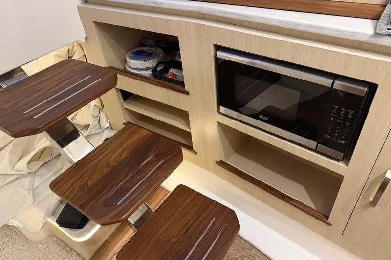 Slide: The Image of Modern kitchen area in 2025 Regal LX43 yacht with microwave and wooden steps. - 16