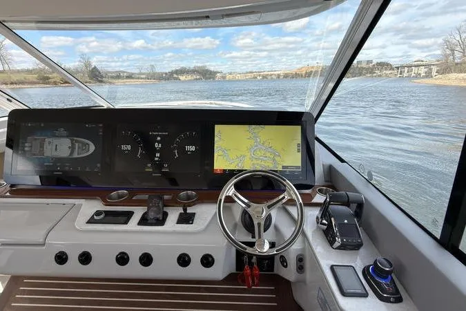 Slide: The Image of Cockpit view of 2025 Regal LX43 boat with advanced navigation system on a scenic lake. - 49