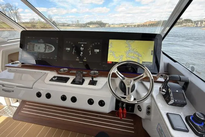 Slide: The Image of Helm of 2025 Regal LX43 boat with advanced navigation displays and steering wheel. - 54
