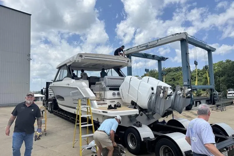 Slide: The Image of 2025 Regal LX43 yacht on trailer at marina, with people inspecting. - 9