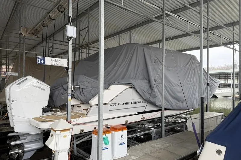 Slide: The Image of Covered 2025 Regal LX43 boat in marina storage, sheltered under a metal roof. - 90