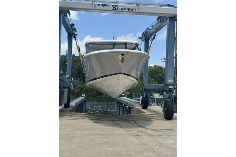 Slide: The Image of 2025 Regal LX43 boat on a lift, ready for launch at a marina. - 93